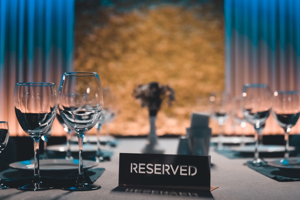 Tables in a restaurant with clean, shiny wine glasses and a reserved sign